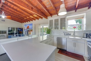 A modern kitchen with white cabinets, stainless steel appliances, and a large island.