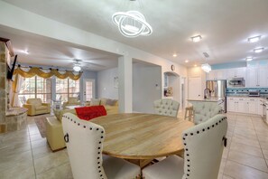 Amplia sala de estar con una gran mesa de comedor de madera, asientos cómodos y una cocina equipada con electrodomésticos modernos.
