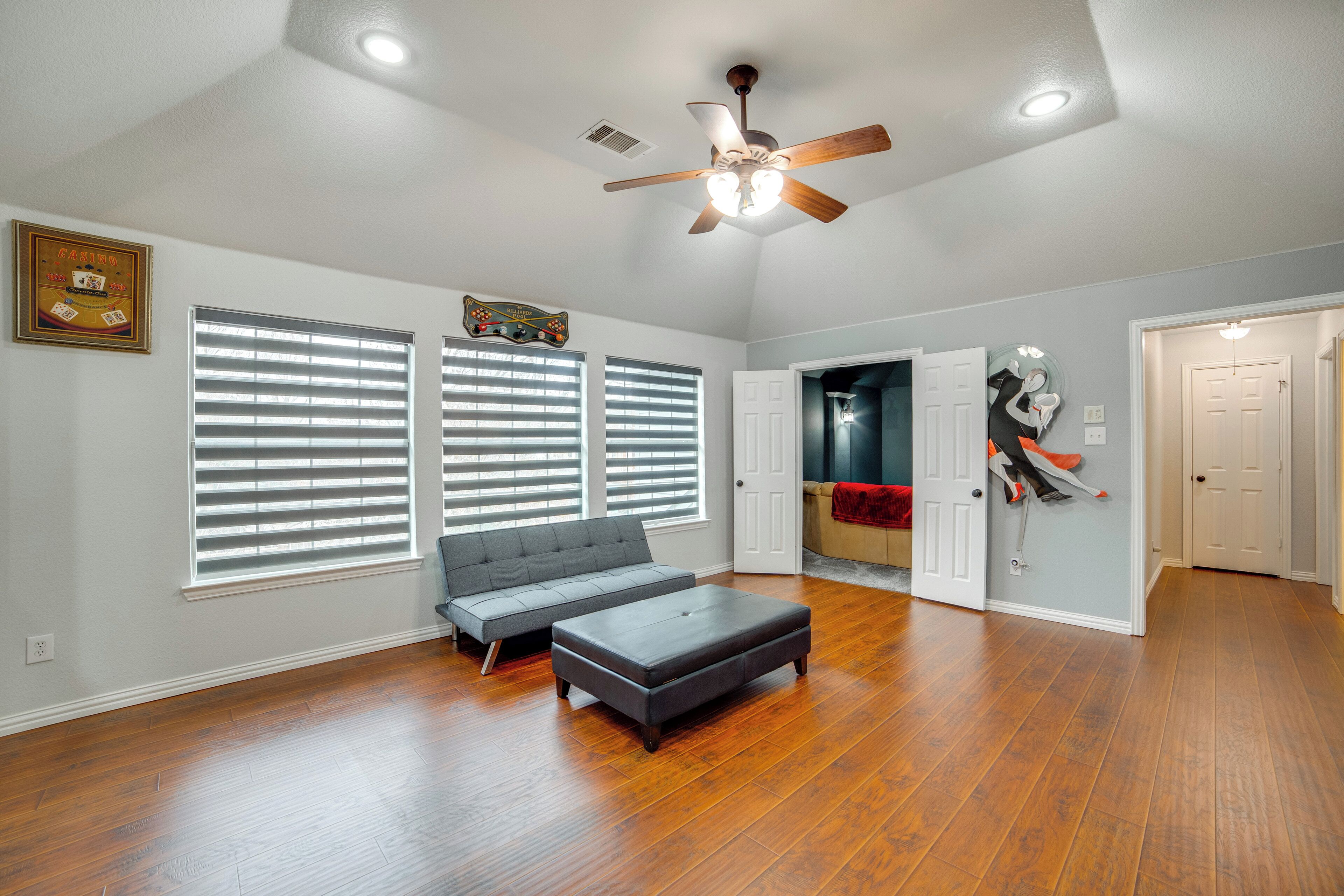 A spacious living room with hardwood flooring, a ceiling fan, and a gray sectional sofa.