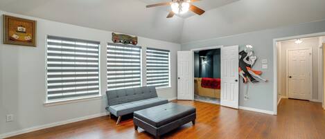 A spacious living room with hardwood flooring, a ceiling fan, and a gray sectional sofa.