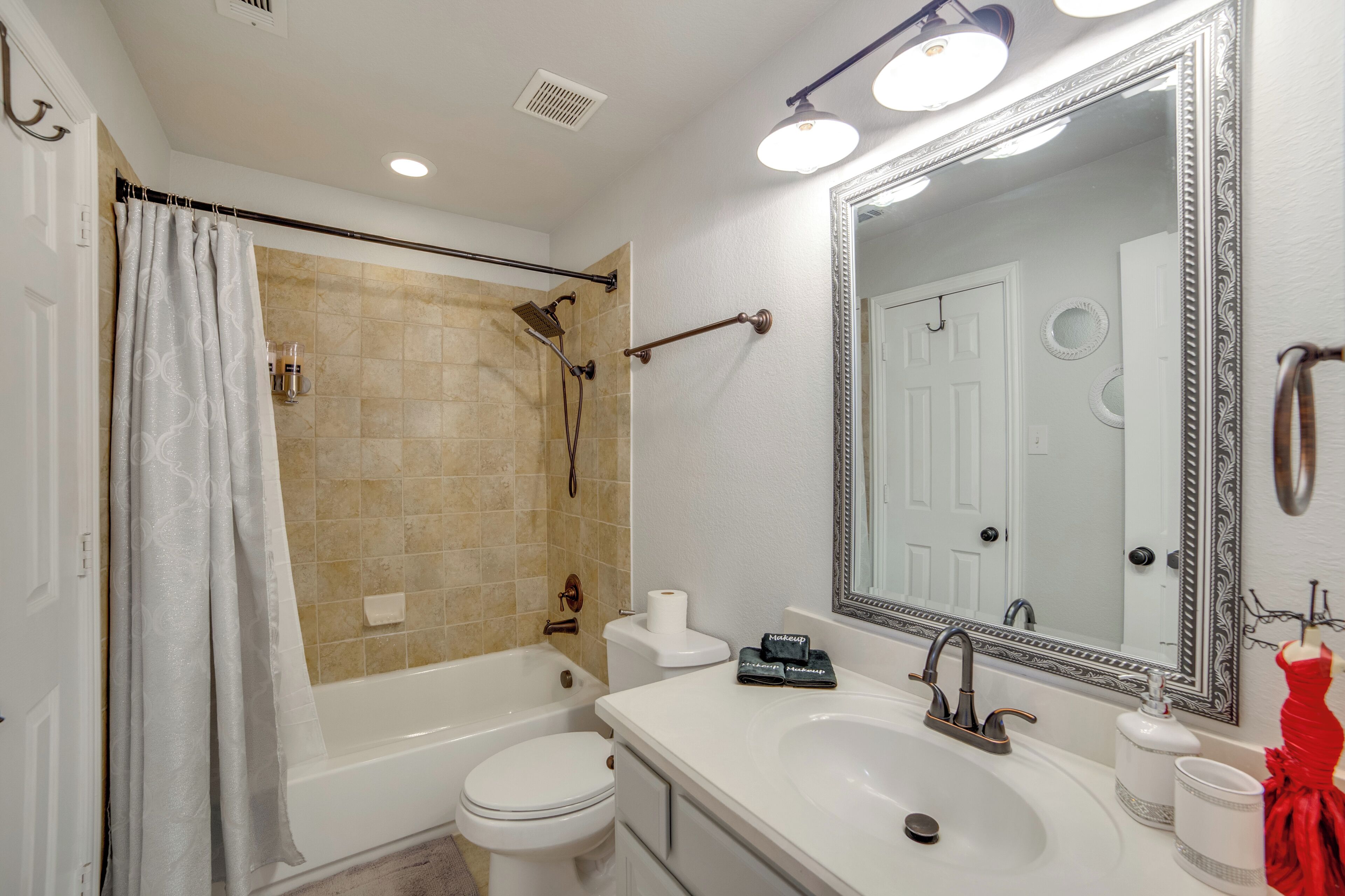 A bathroom with a bathtub, toilet, sink, and a large mirror.
