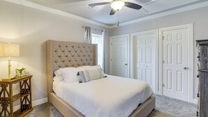 A bedroom with a tufted headboard, a bed with white bedding, a bedside table with a lamp, and a ceiling fan. - Fully Updated & Convenient! Baytown Home Near Dtwn (Baytown)