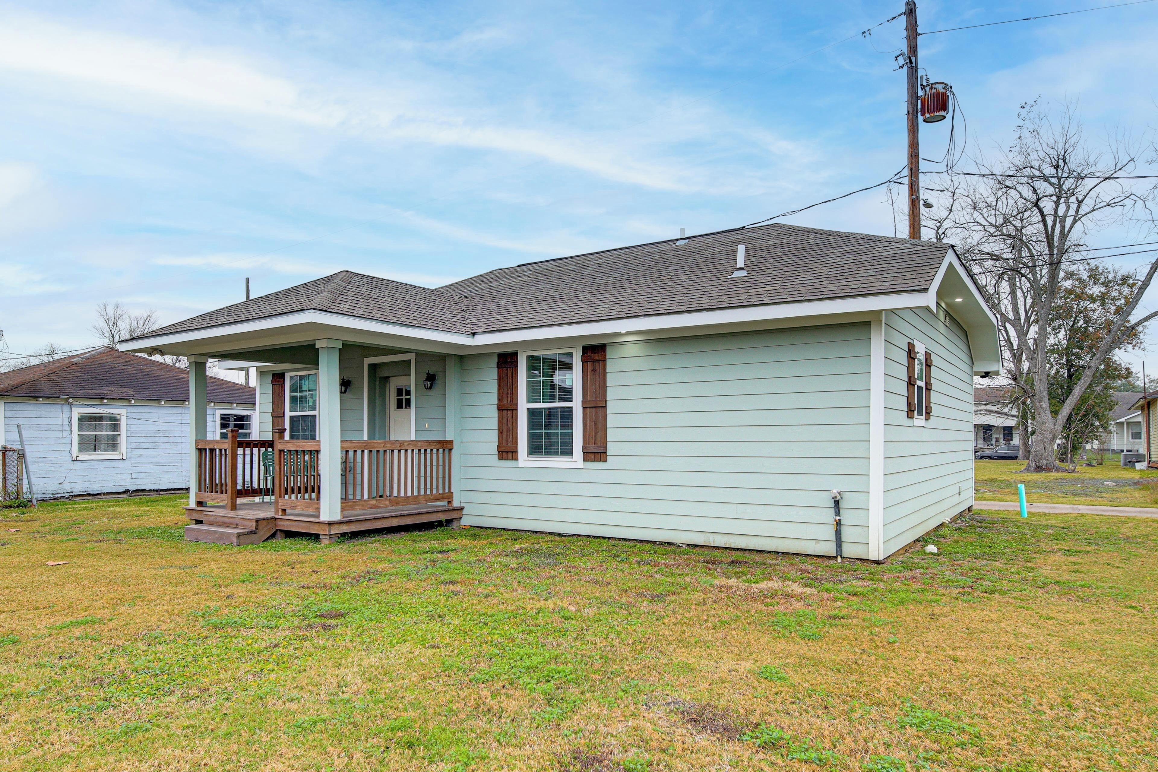 A single-story house with a porch, a small front yard, and a utility pole nearby.