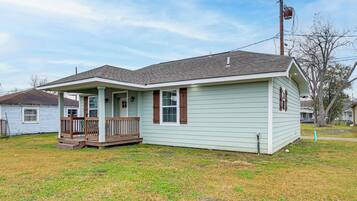A single-story house with a porch, a small front yard, and a utility pole nearby.