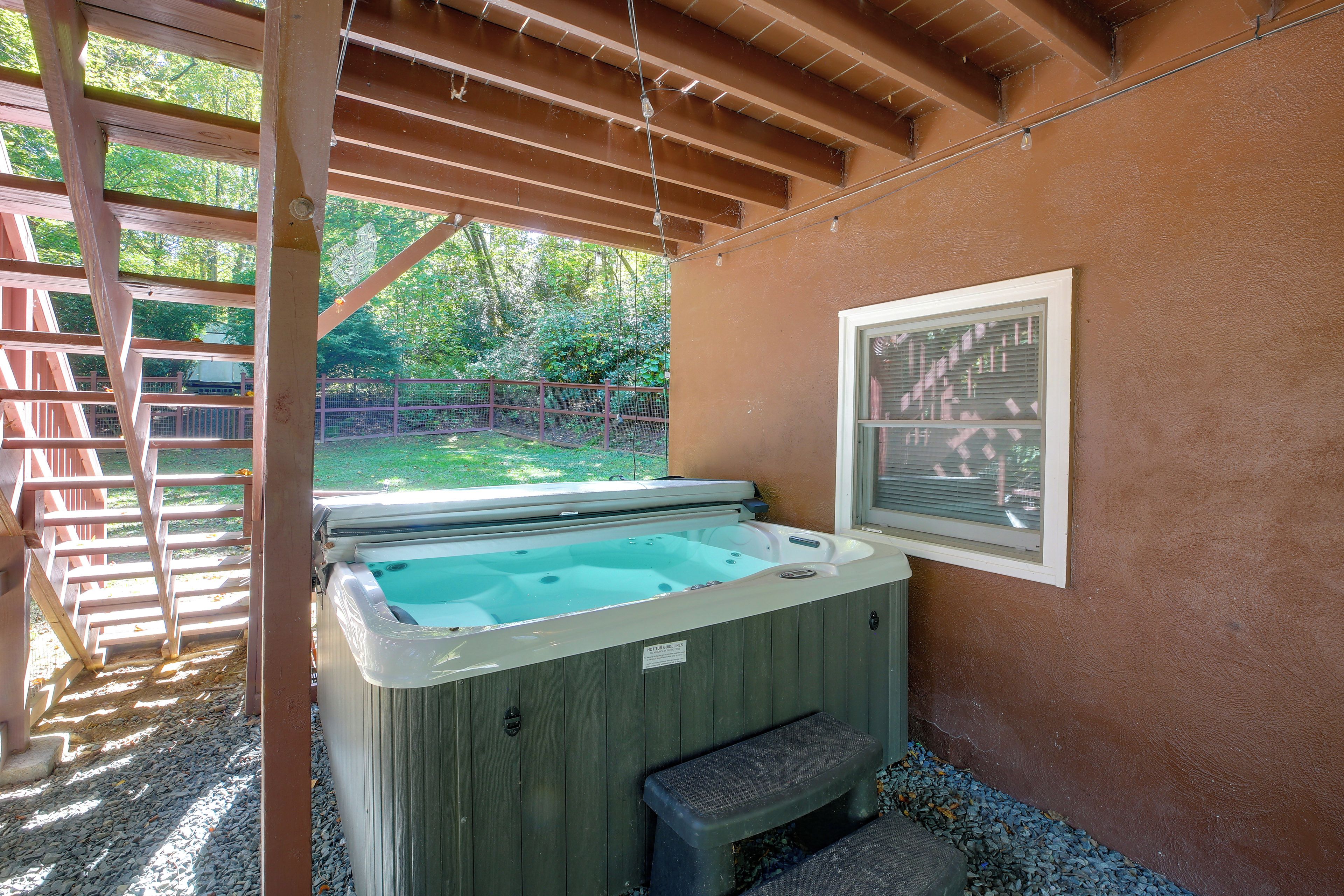 A hot tub with a wooden deck and a window.