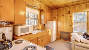 A compact kitchen with wooden cabinets, a stove, a microwave, and a refrigerator. - Close to Lake & Heavenly Mtn Resort! Quaint Cabin (South Lake Tahoe)