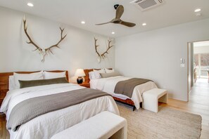 Quarto de hotel com duas camas, um ventilador de teto e decoração de chifres na parede.