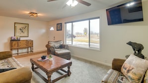 A living room with a ceiling fan, a large window, a sofa, a coffee table, and a fireplace. - 5 Mi to Heise Hot Springs: 'the Trout House' (Ririe)