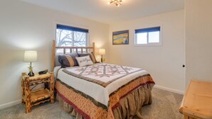 A bedroom with a large bed, a nightstand with a lamp, and two windows. - 5 Mi to Heise Hot Springs: 'the Trout House' (Ririe)