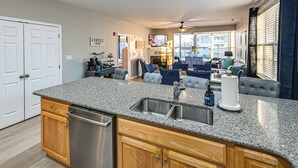 A modern kitchen with granite countertops, stainless steel appliances, and wooden cabinets. - Bay-n-beach! Comfy Coastal Condo in Lewes! (Lewes)