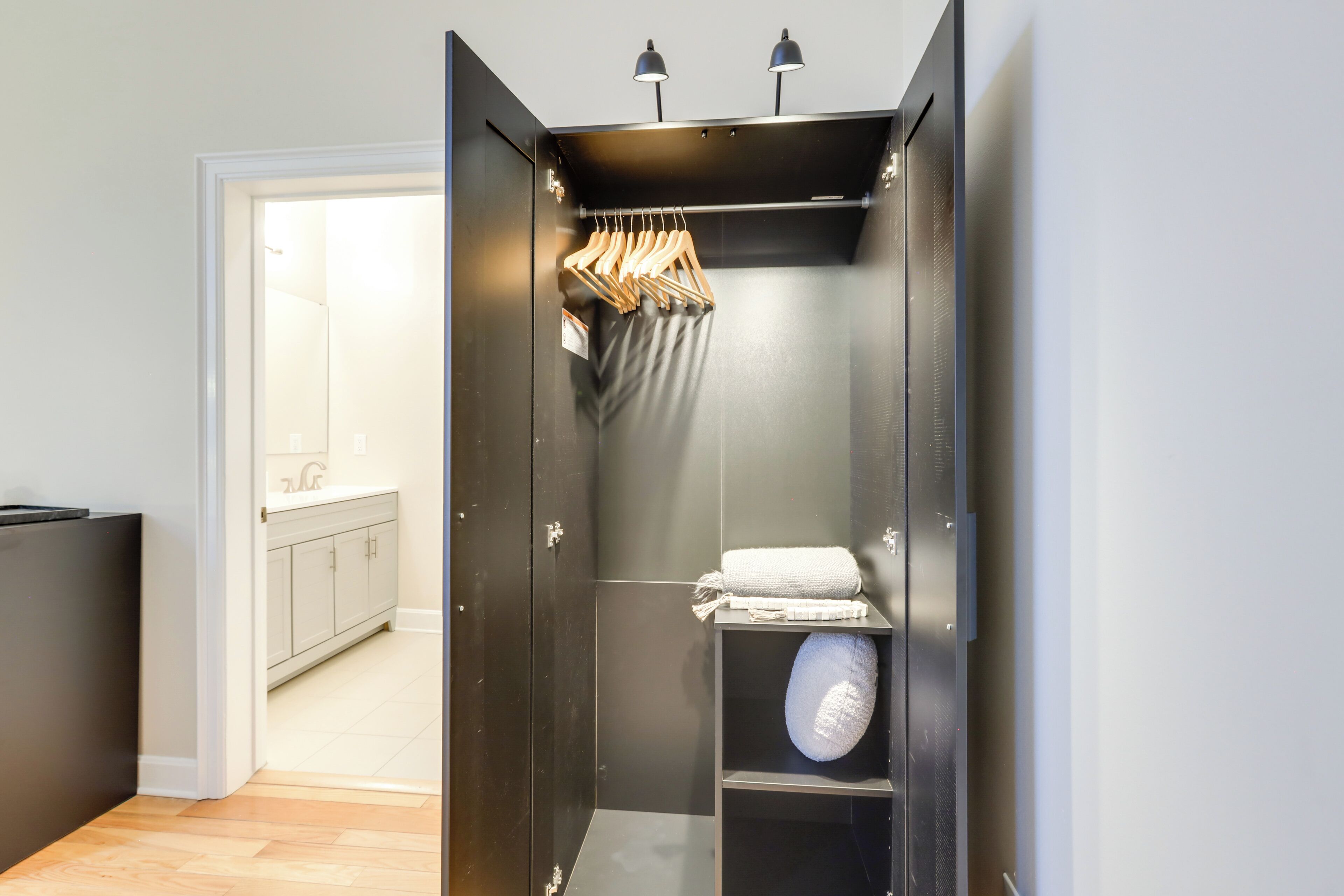 Ein kleines, modernes Badezimmer im dunklen Stil mit Duschbereich, Handtuchhalter und Ablage für ein Handtuch.