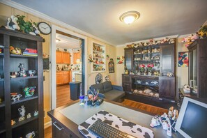 A room with a desk, shelves with various items, a couch, and a kitchen area visible through an open door. - Private Yard & Patio Bbq! Norfolk Home Near Dtwn (Norfolk)