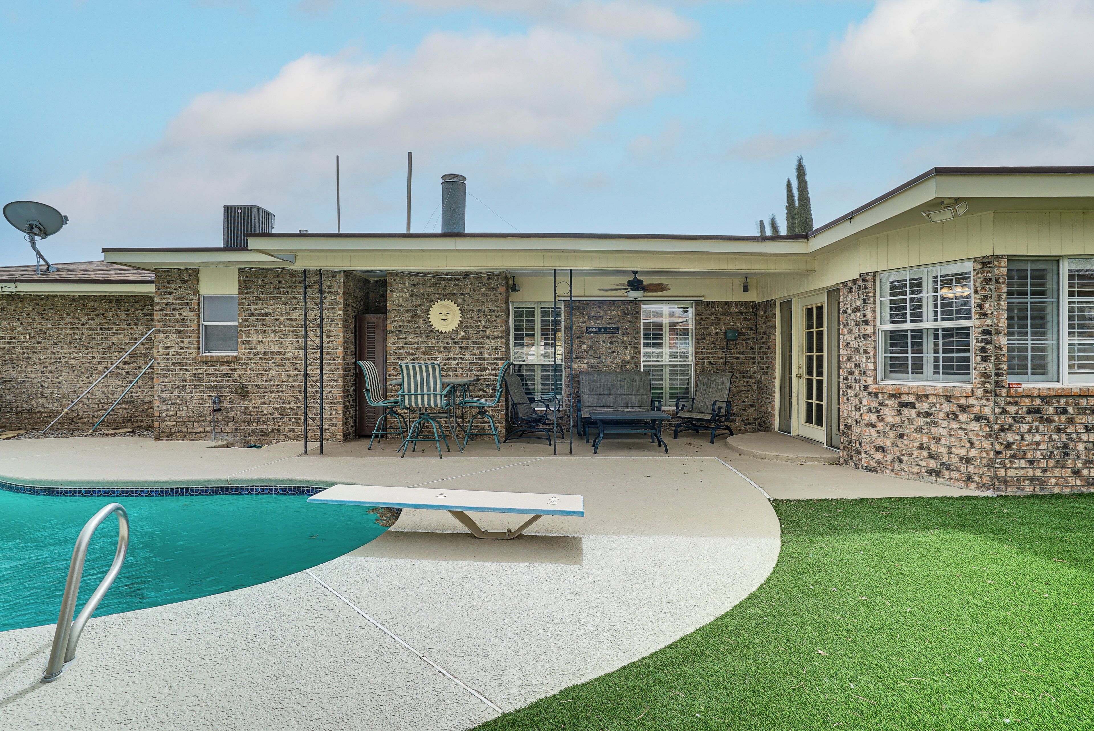 A house with a swimming pool, outdoor furniture, and a brick exterior.