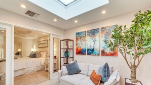 A modern living room with a sofa, a coffee table, and a large window. - 11 Mi to Coachella: Palm Desert Gem w/ Pool Access (Palm Desert)