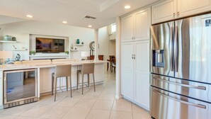 A modern kitchen with a stainless steel refrigerator, a built-in oven, and a bar area with stools. - 11 Mi to Coachella: Palm Desert Gem w/ Pool Access (Palm Desert)