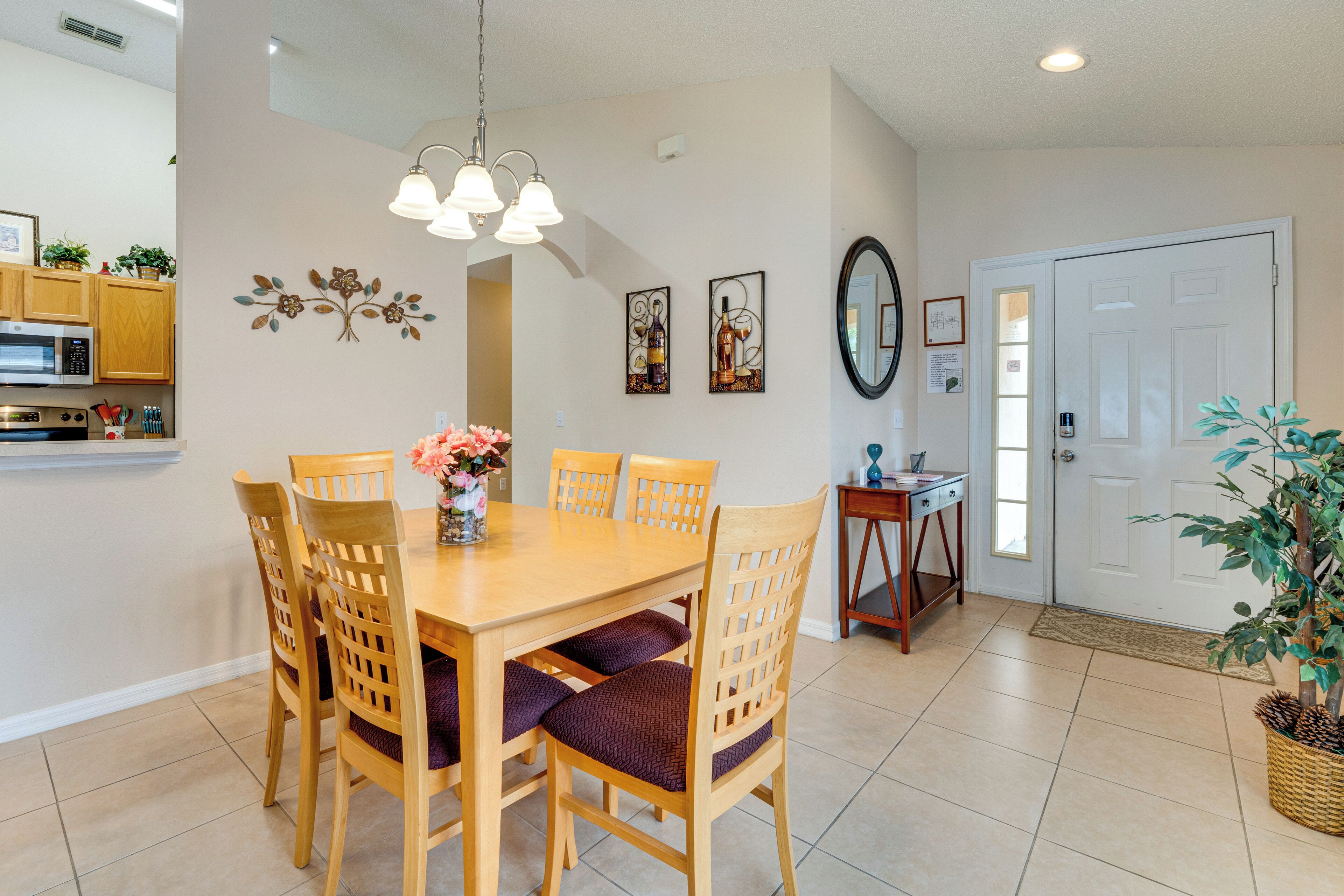 A dining area with a wooden table and chairs, a chandelier, and wall decorations.