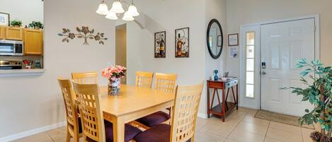 A dining area with a wooden table and chairs, a chandelier, and wall decorations.