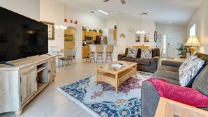 A spacious living room with a large flat-screen TV, a wooden coffee table, and a patterned rug. There is a sofa with decorative pillows and a ceiling fan. - Poolside Oasis & Game Room Fun! Gem in Haines City (Haines City)