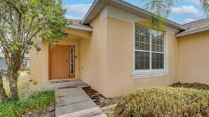 A single-story house with a beige exterior, a front door, and a window. - Poolside Oasis & Game Room Fun! Gem in Haines City (Haines City)