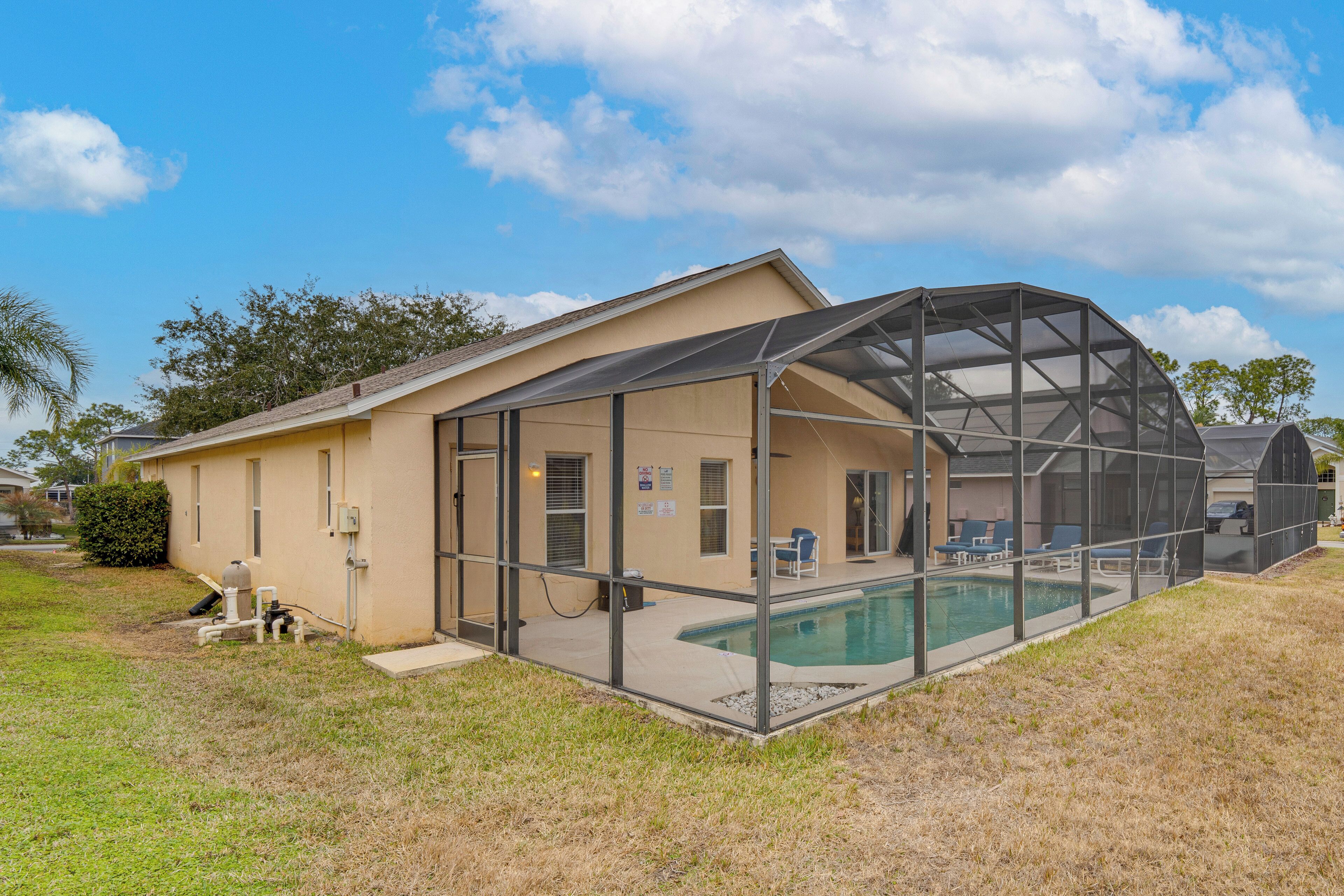 A house with a covered outdoor pool area, a garage, and a small lawn.