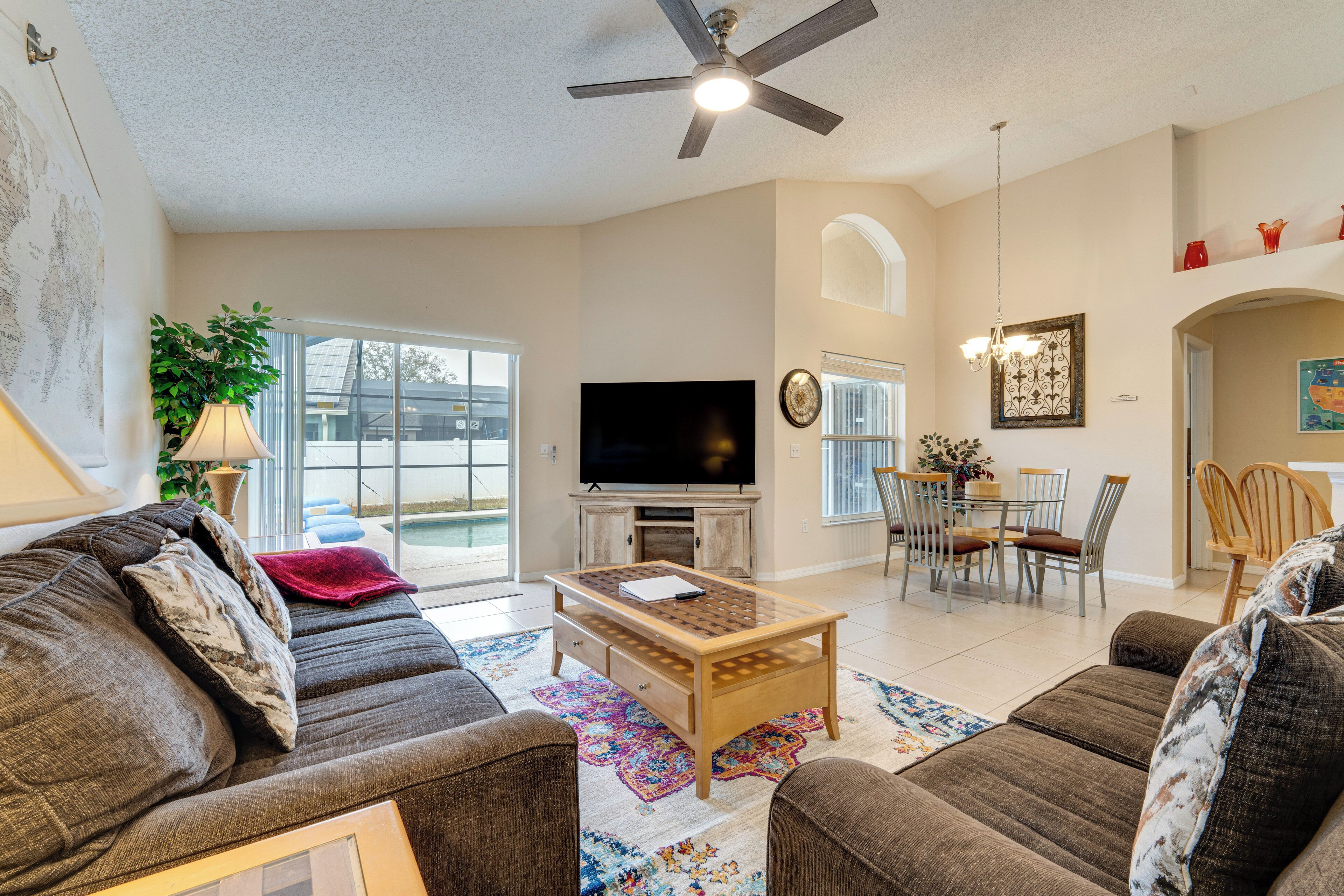 A spacious living room with a large TV, comfortable sofas, a wooden coffee table, and a dining area with chairs and a table.
