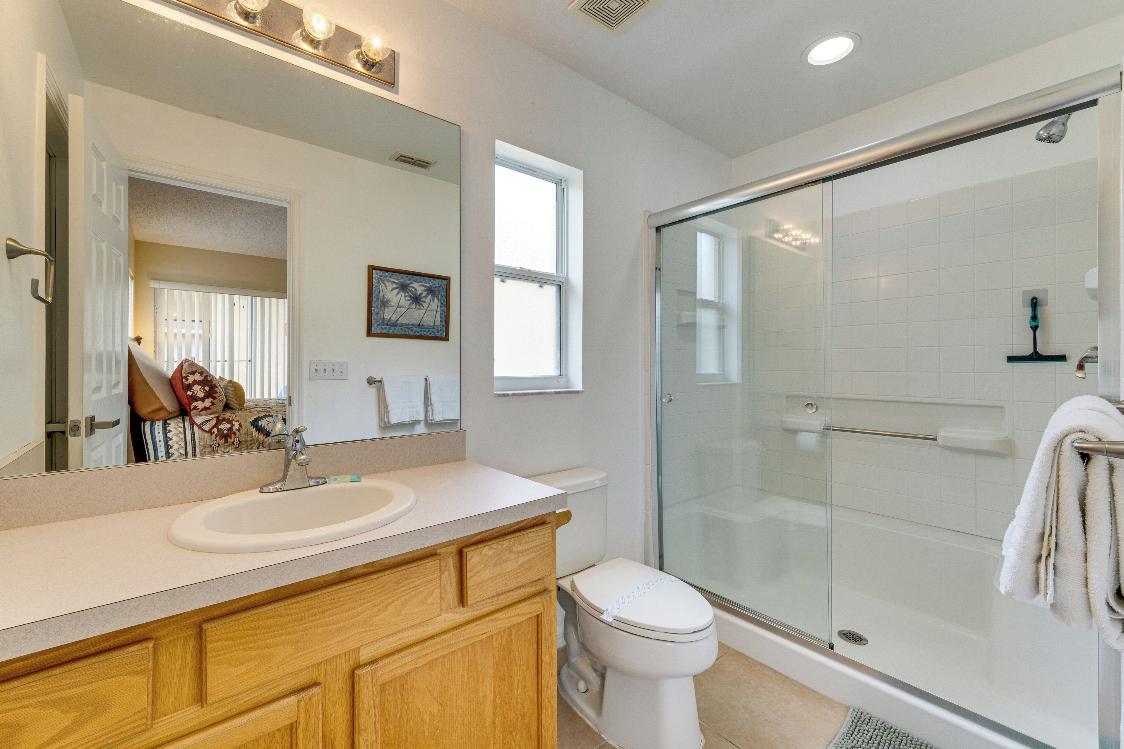 Un baño moderno con cabina de ducha de vidrio, tocador de madera y un espejo grande.
