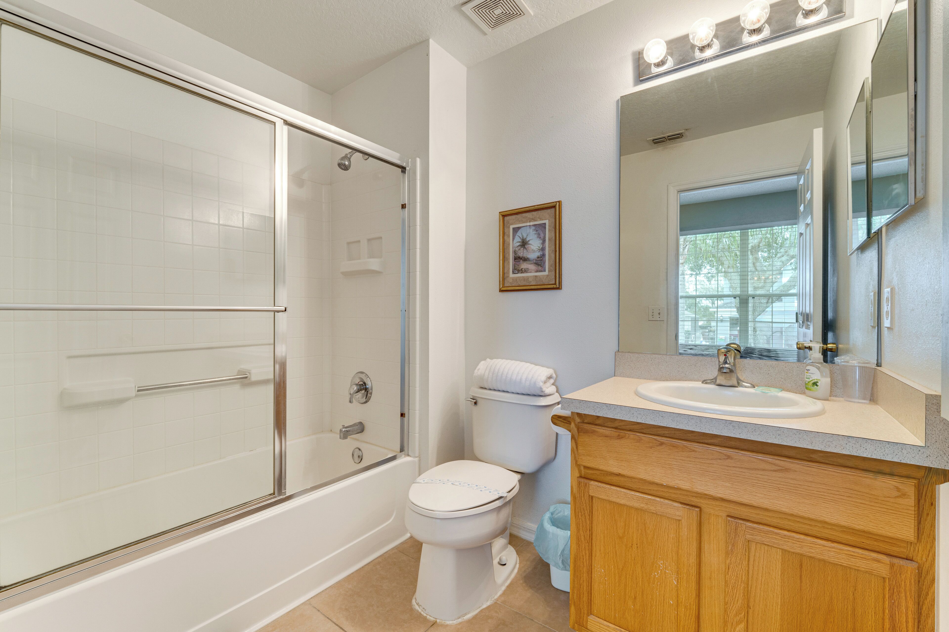 A bathroom with a glass-enclosed shower, a toilet, and a sink with a mirror above it.