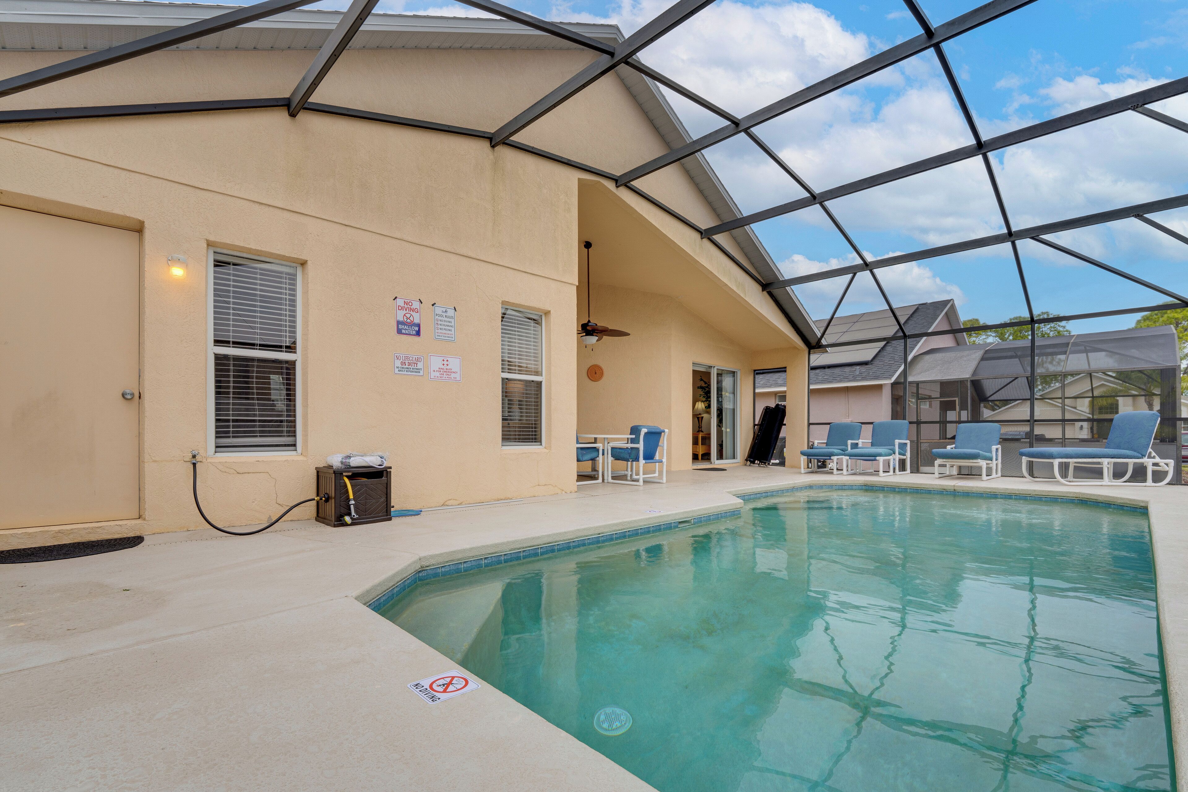 An indoor swimming pool with clear blue water, surrounded by lounge chairs and a covered area with a glass ceiling.