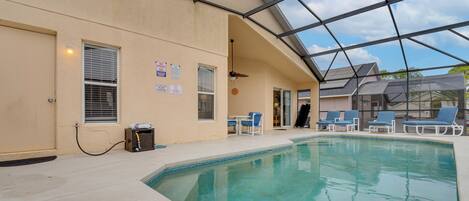 An indoor swimming pool with clear blue water, surrounded by lounge chairs and a covered area with a glass ceiling.