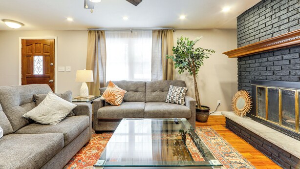 Ein Wohnzimmer mit einer Couch, einem Couchtisch, einem Kamin und einem Deckenventilator.
