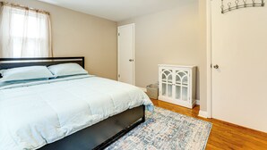 Ein Schlafzimmer mit einem Bett, einem weißen Schrank, einer Tür und einem Fenster mit Vorhängen.