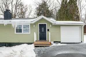 A single-story house with a dark front door, a garage, and a small porch. - Pet-friendly Home: 5 Mi to Downtown Syracuse! (Syracuse)