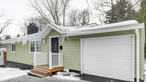 Ein eingeschossiges Haus mit Veranda, Garage und Schornstein.