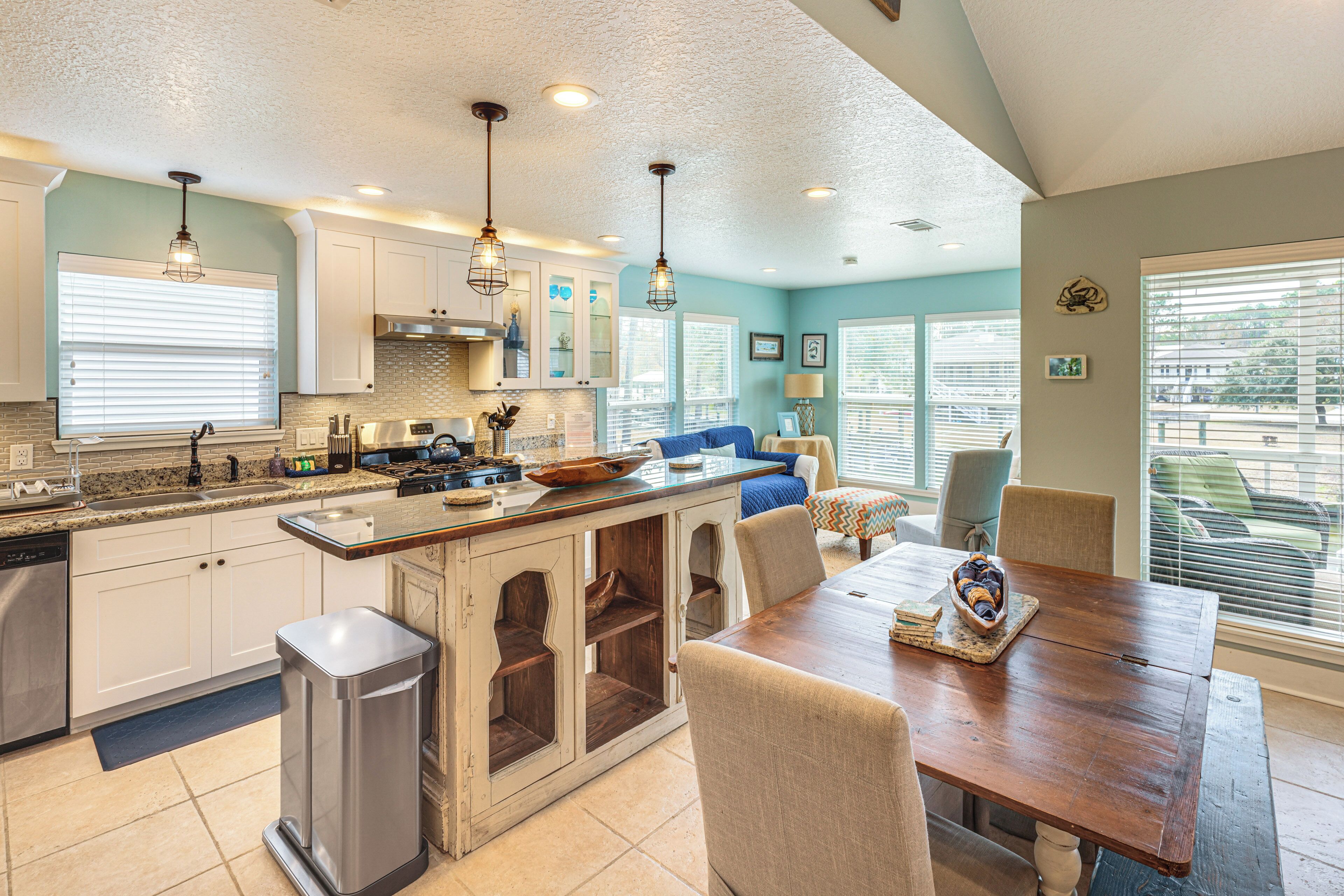 A modern kitchen with a central island, built-in cabinets, and pendant lighting.