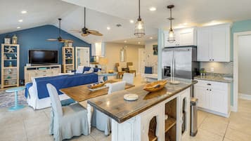 A spacious living room with a large TV, comfortable seating, and a kitchen area with modern appliances.