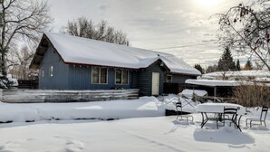 Una cabaña de madera con techo nevado y un pequeño porche.