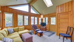 Un salon spacieux avec un grand canapé, un meuble de rangement en bois et un téléviseur.