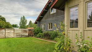 Une cabane en rondins avec une pelouse bien entretenue et une clôture en bois.