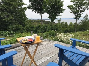 Un terrazza in legno con un tavolo apparecchiato per la colazione, con vista su un lago.