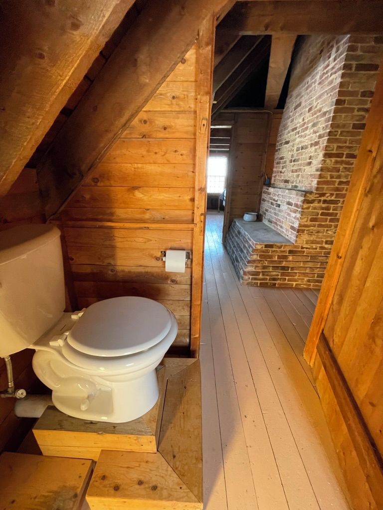 A wooden cabin with a single toilet in a small, enclosed space.