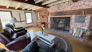 A living room with a fireplace, leather sofas, and a coffee table. - Private Beach! Passamaquoddy Bay Cottage (Perry)