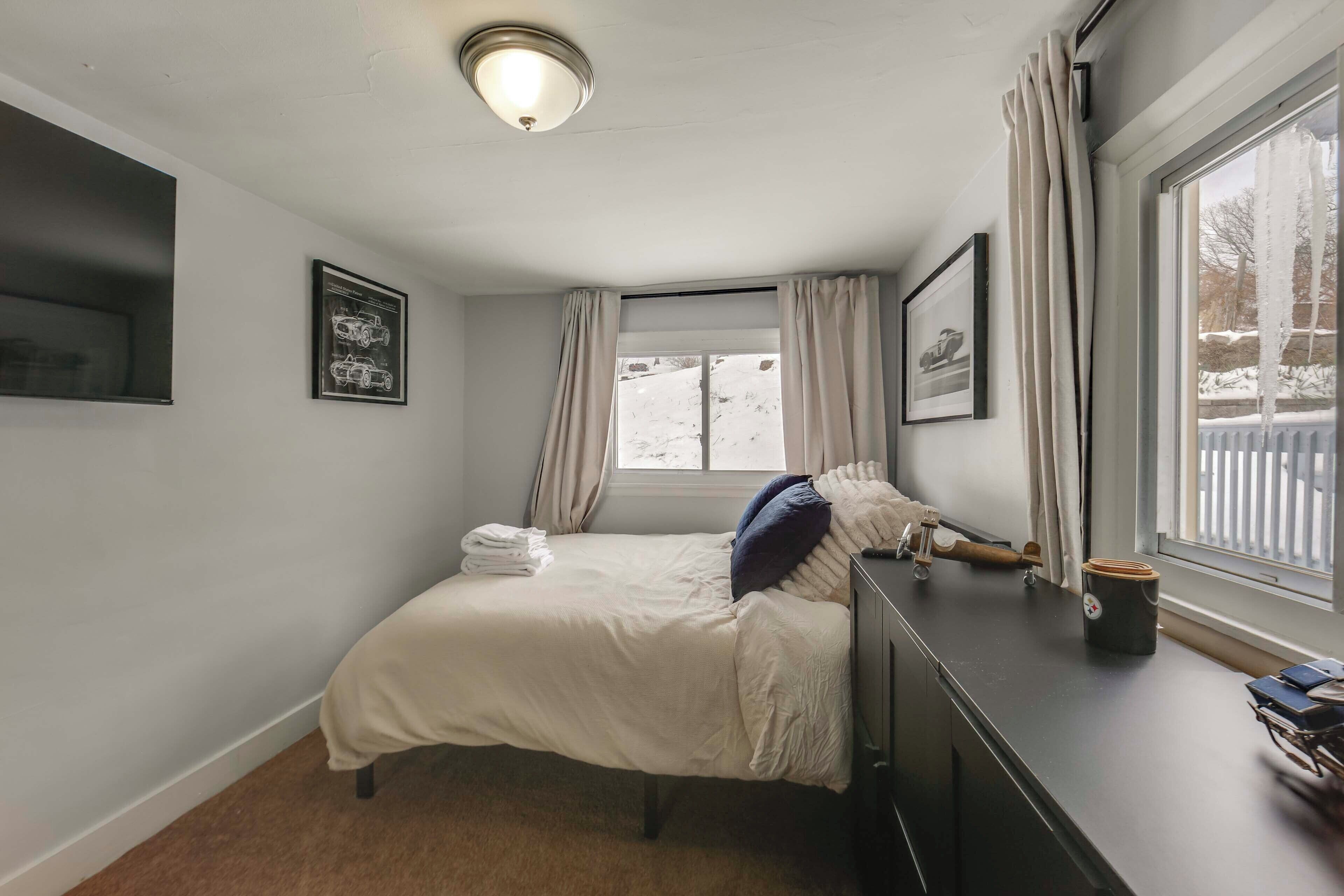 Un dormitorio con cama, cómoda, ventana con cortinas e imagen enmarcada en la pared.