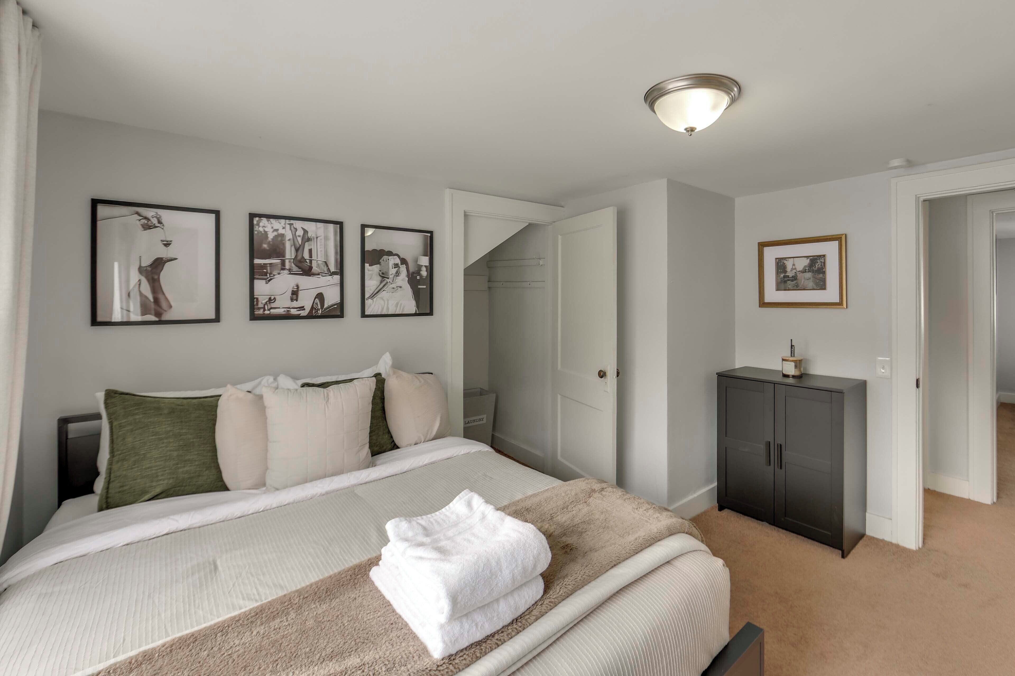 A bedroom with a bed, a wardrobe, and three framed pictures on the wall.