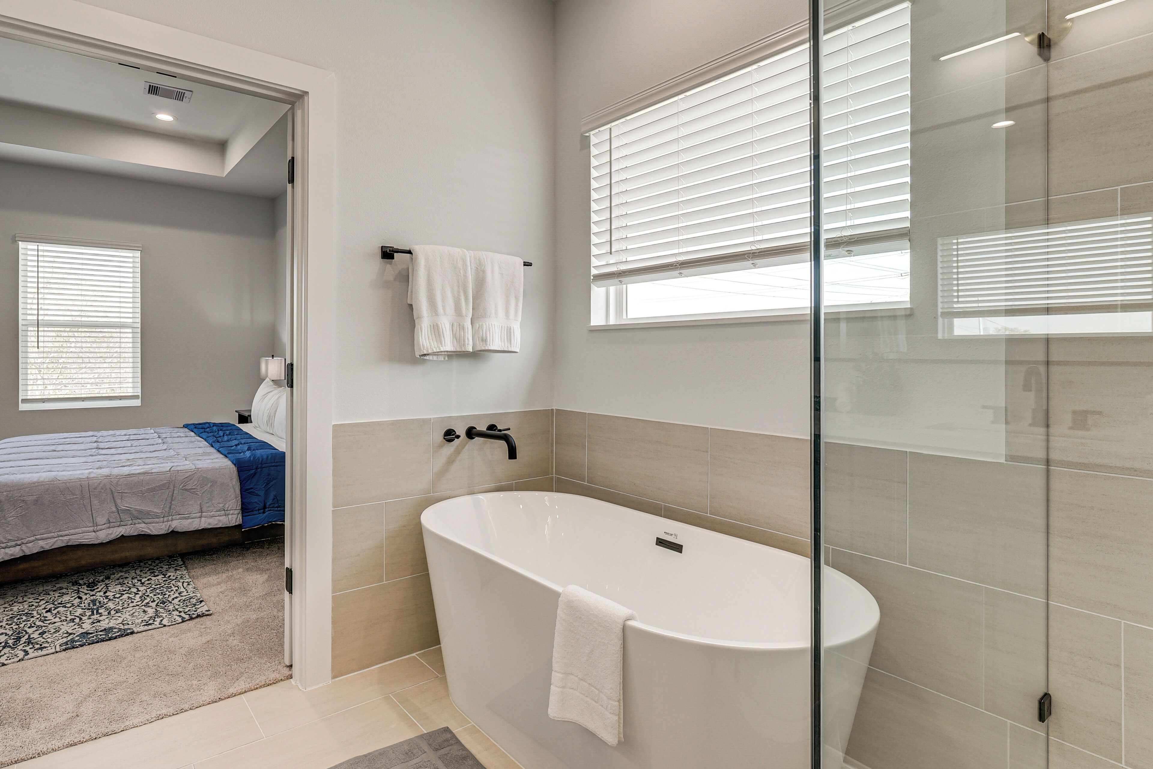 A modern bathroom with a freestanding bathtub, a glass shower enclosure, and a visible showerhead.