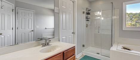 Un baño con lavabo, espejo, ducha y bañera.