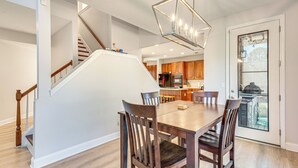 A dining area with a wooden table and chairs, a staircase, and a kitchen in the background. - Outdoor Kitchen! Spacious Stone Mountain Retreat (Stone Mountain)