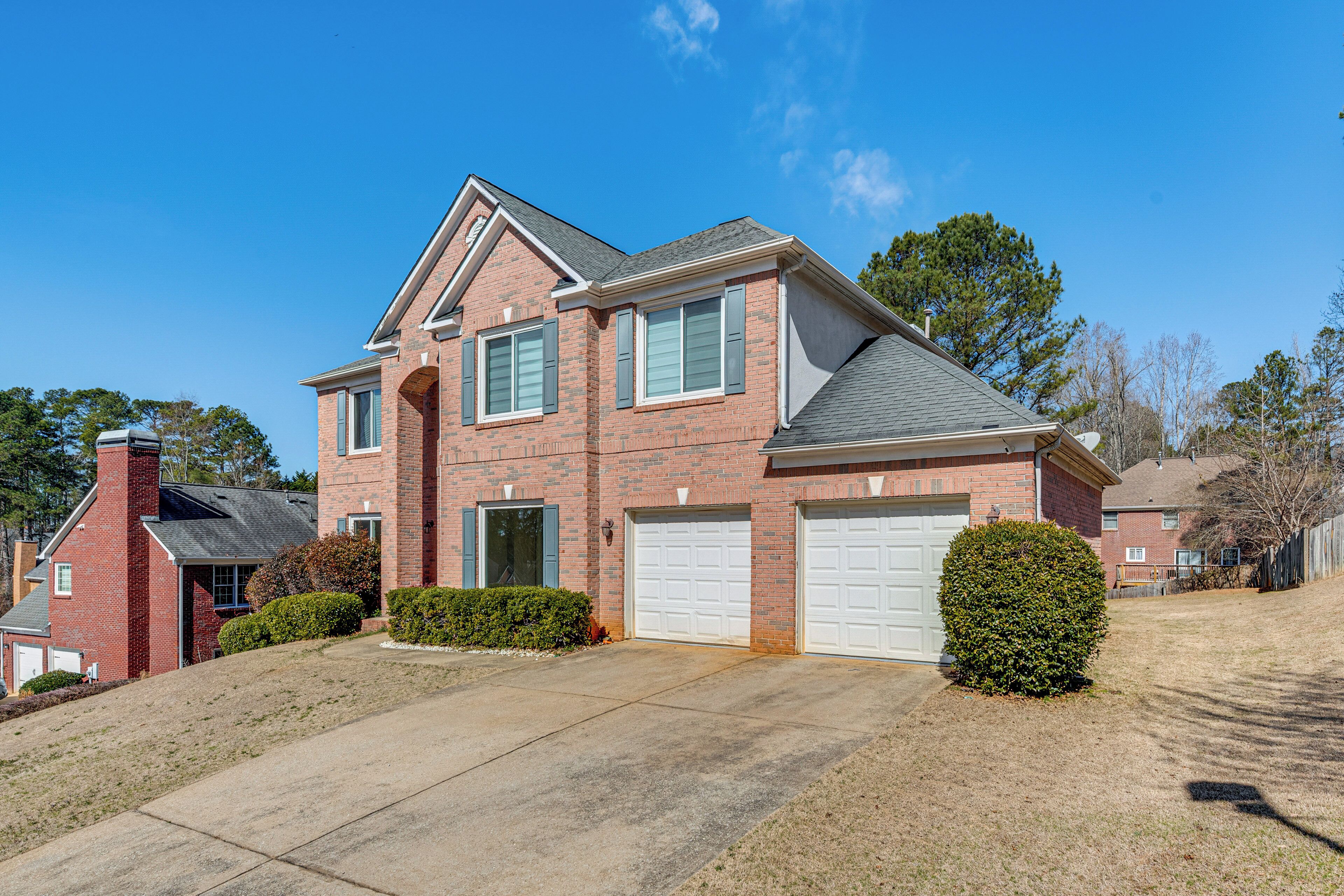 A two-story brick house with a garage, a covered front porch, and a well-maintained lawn.