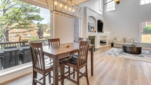 A dining area with a wooden table and chairs, a chandelier, and a view of the outside. - Outdoor Kitchen! Spacious Stone Mountain Retreat (Stone Mountain)