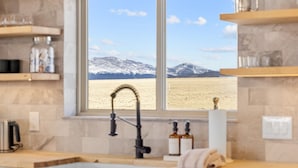 Una cocina con un amplio ventanal que ofrece vistas a un paisaje montañoso nevado.