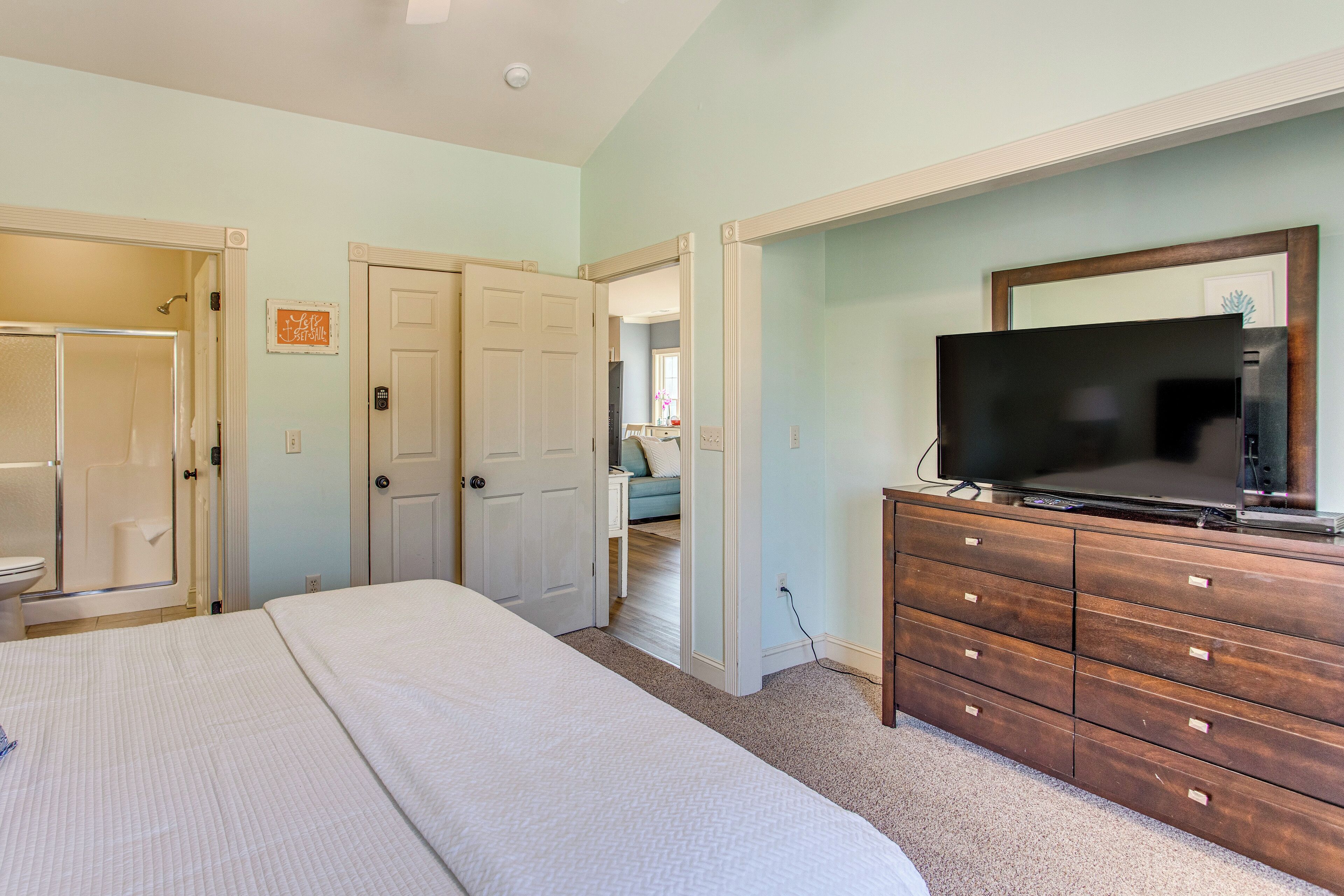 A bedroom with a bed, a dresser with a TV, and a bathroom with a shower.